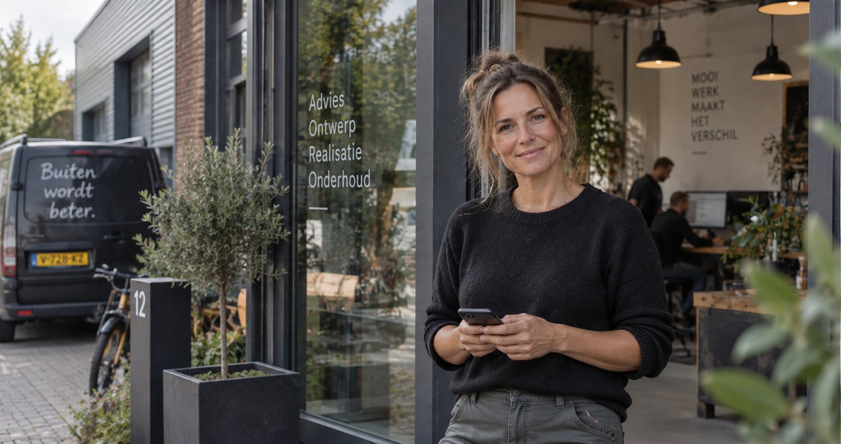 Nederlandse MKB-ondernemer met telefoon voor haar eigen bedrijfspand, team aan het werk binnen